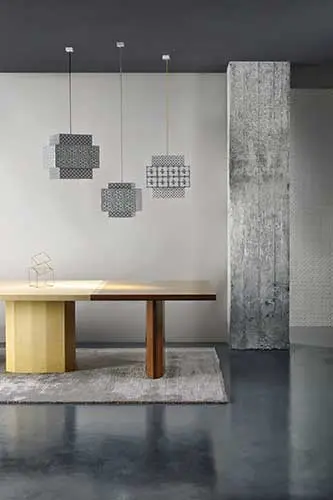 Geometric pendant lights over a two-tone wood dining table on a polished concrete floor