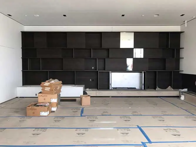 Living room under construction with dark modular wall shelving and cardboard boxes on the floor