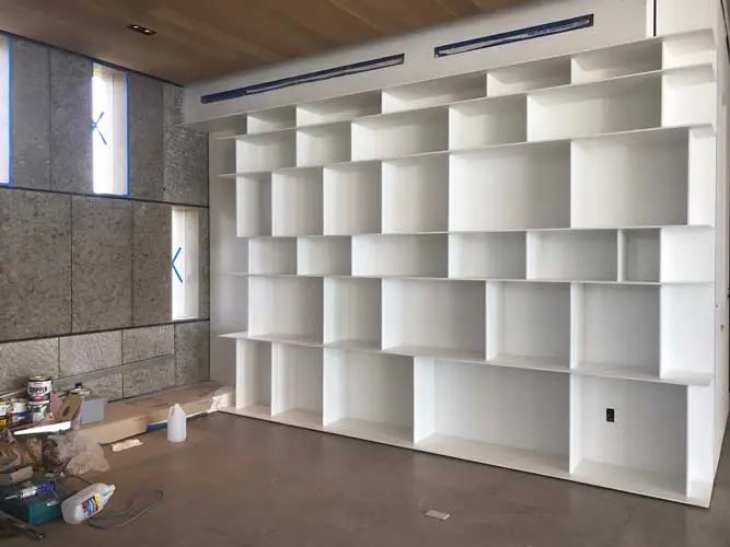 large white modular bookshelf under construction with taped-up windows