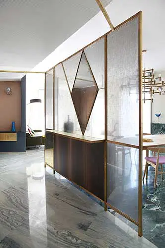 Brass-framed glass room divider with a diamond mirror panel in an apartment