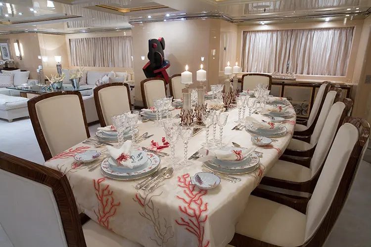 Yacht dining table set for a formal meal with coral-print linens and crystal glasses