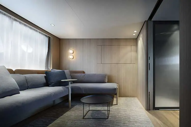 Minimalist wood-paneled cabin lounge with a gray sectional sofa