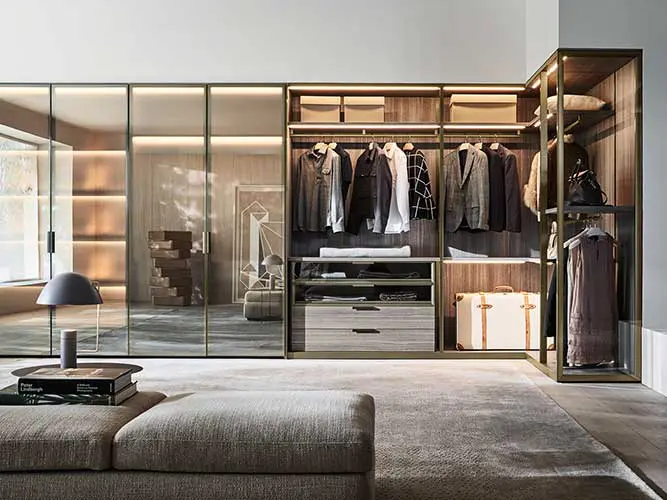 walk-in wardrobe with glass-front closets, hanging clothes and a suitcase