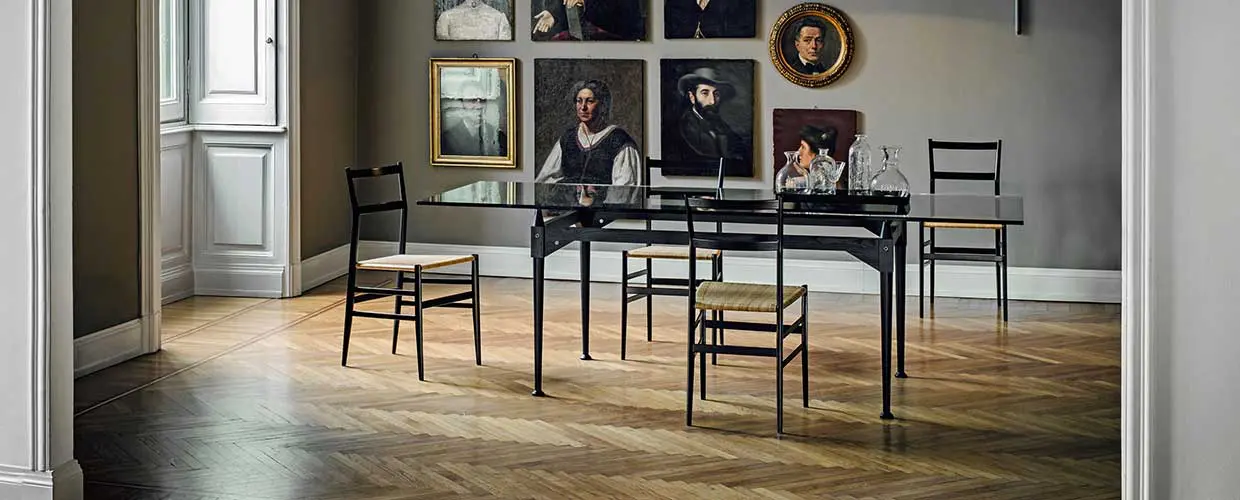 dining room with a black table and chairs beneath framed portrait paintings