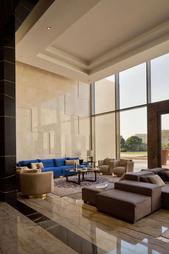hotel lobby lounge with a blue sofa and beige armchairs beneath tall columns