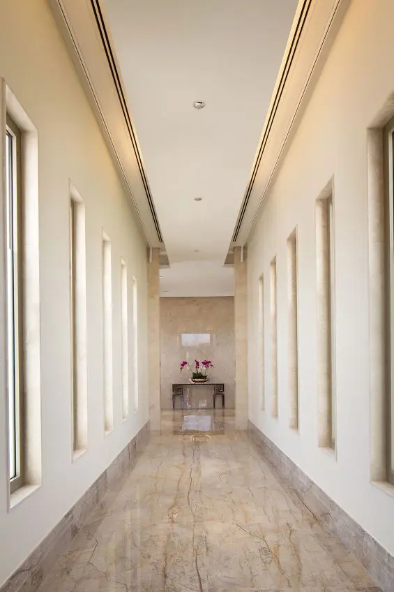 Marble hallway with arched wall niches leading to a flower arrangement