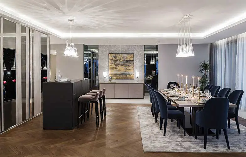 Dark elegant dining and kitchen space with a herringbone floor and pendant lights