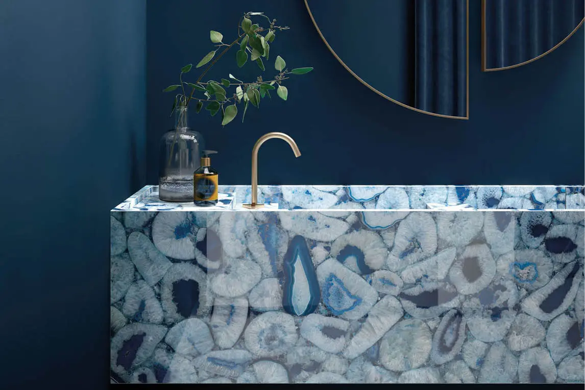 Blue agate wash basin with a brass tap against a dark blue wall