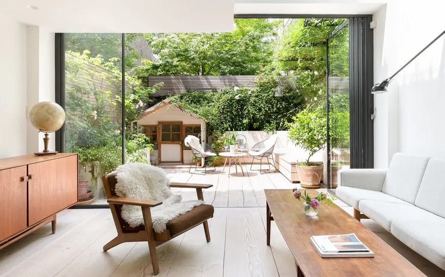 Bright living room with a mid-century armchair, sofa and glass doors opening to a garden