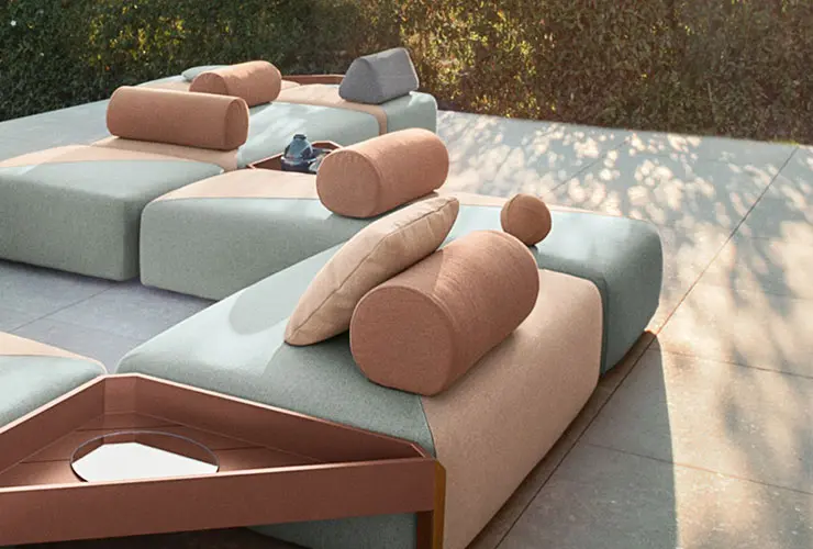 outdoor daybeds with cylindrical bolster cushions on a stone terrace