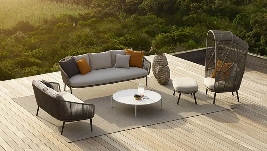 Outdoor terrace with rope furniture, orange cushions and a round white coffee table