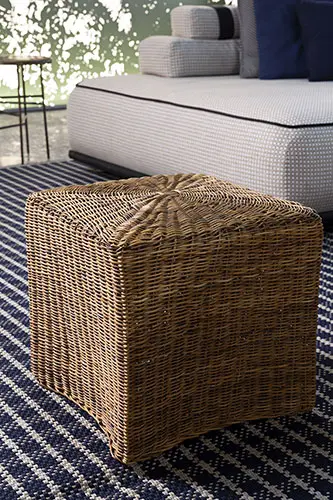 woven wicker ottoman beside an upholstered outdoor daybed