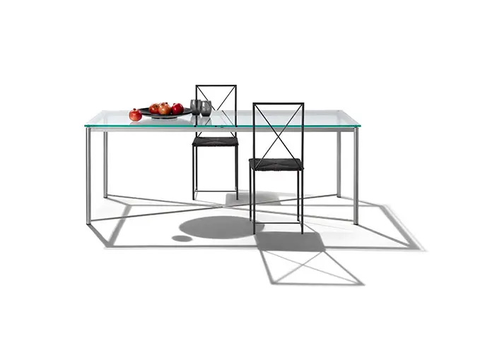 glass dining table with black X-frame chairs and a bowl of fruit
