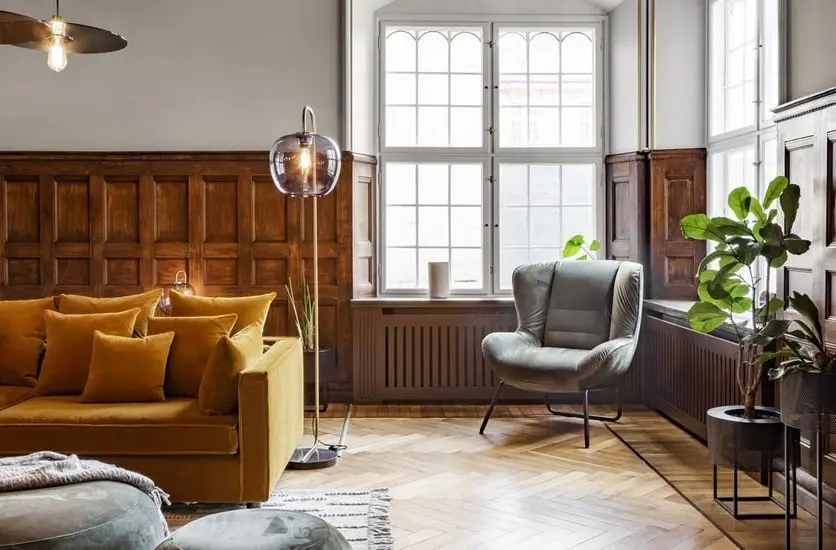 Wood-paneled living room with a mustard sofa and gray armchair