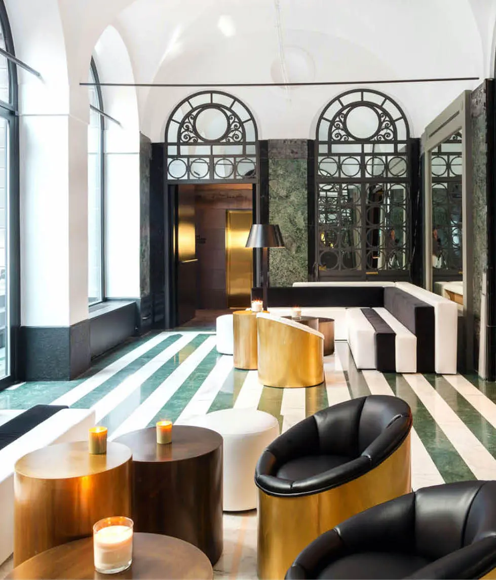 Hotel lounge with green marble floors, gold armchairs and arched mirrored windows