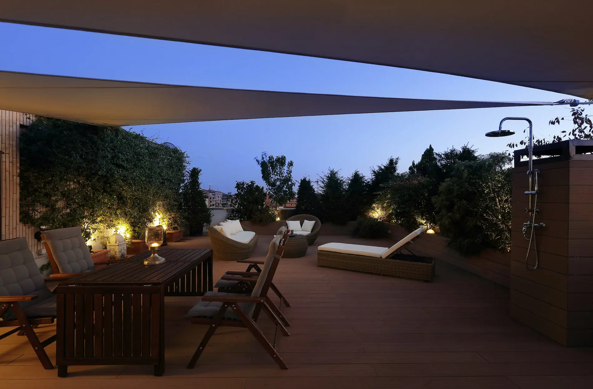 Rooftop terrace at dusk with lounge seating and an outdoor shower