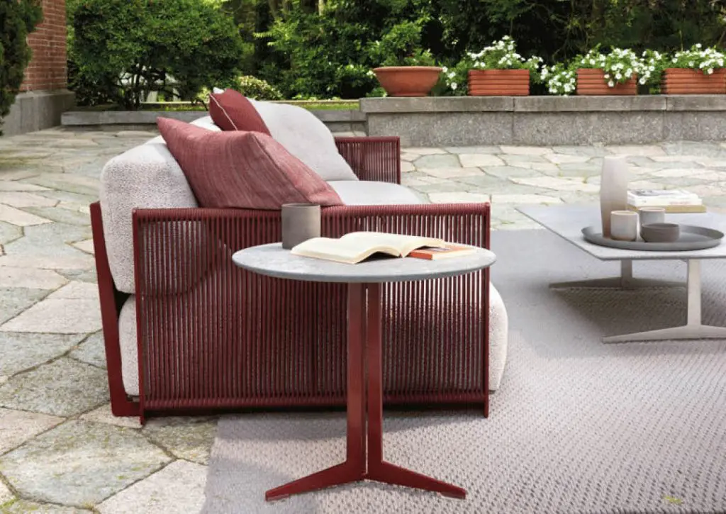Terrace sofa with a burgundy woven frame and grey cushions beside a round marble side table