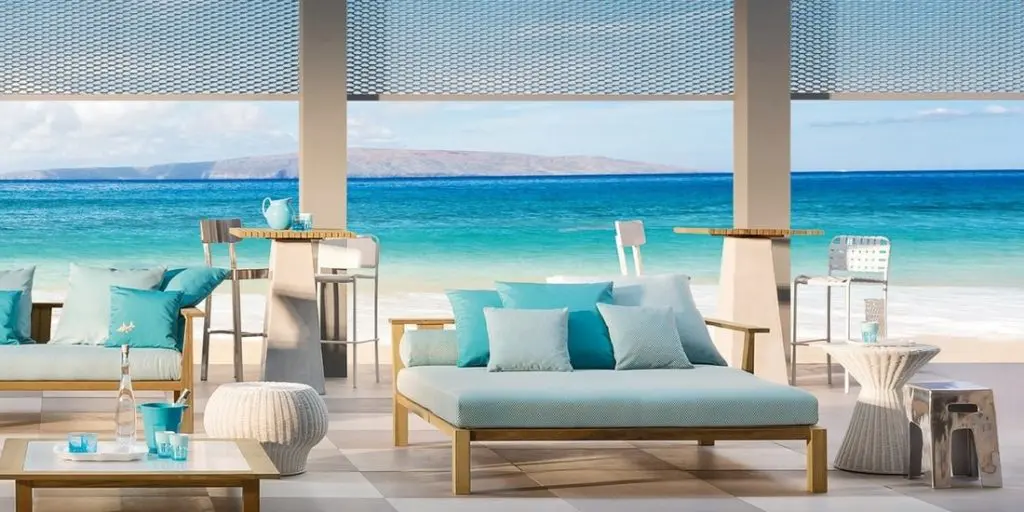 Covered beach terrace with turquoise cushioned daybeds and bar stools facing the ocean