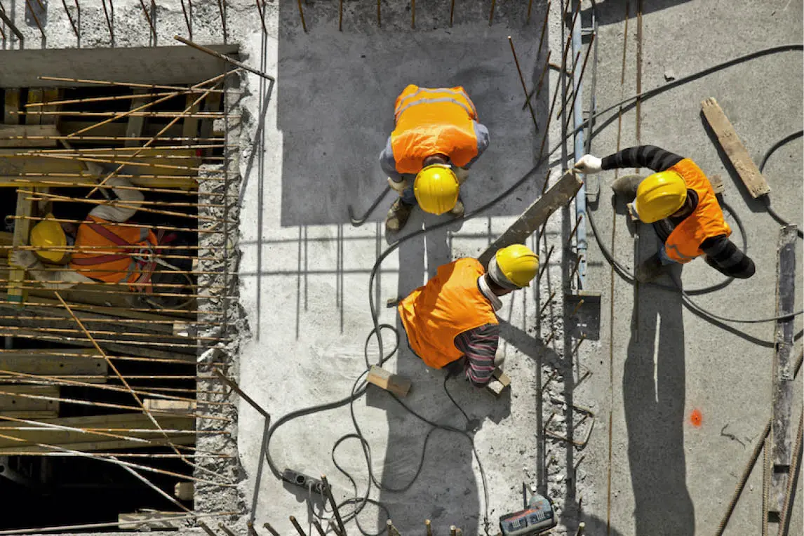 Construction workers in hard hats on a building site, seen from above