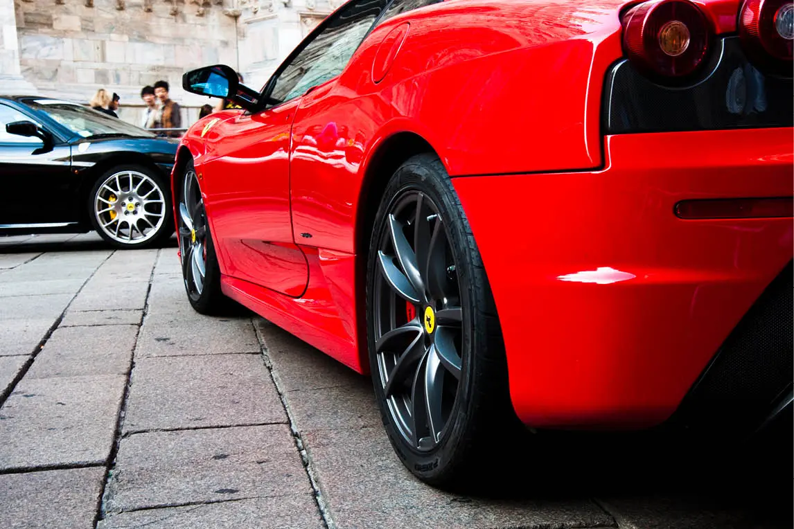 Red sports car parked on a stone-paved street