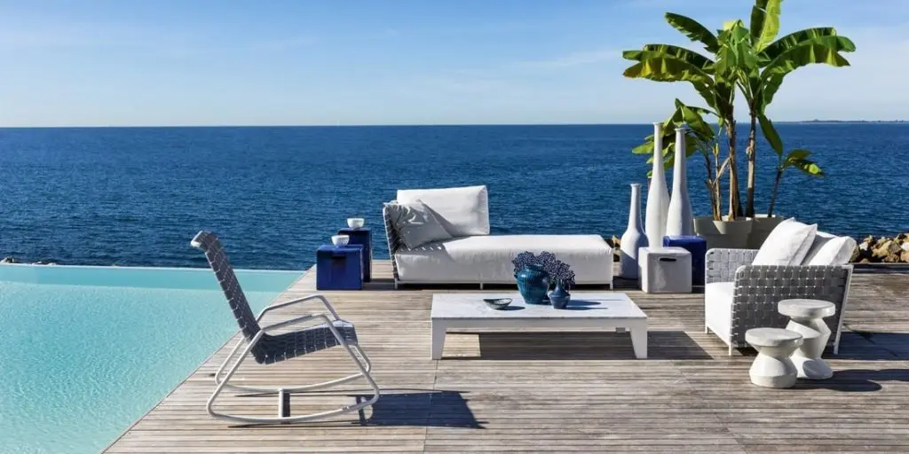 Gervasoni white outdoor sofa and rocking chair on a wooden deck overlooking the sea
