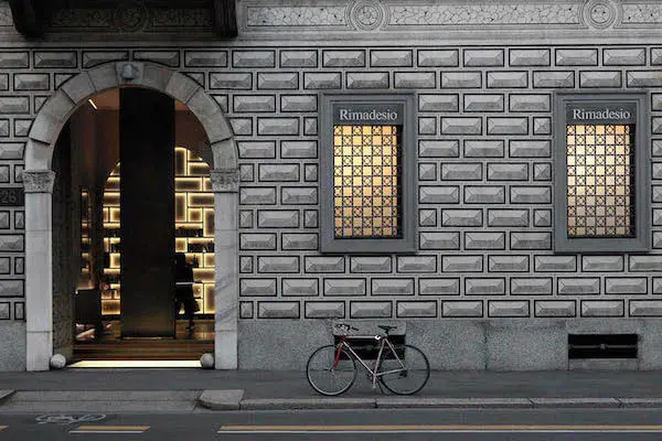 Rimadesio storefront with illuminated display windows on a stone facade at night