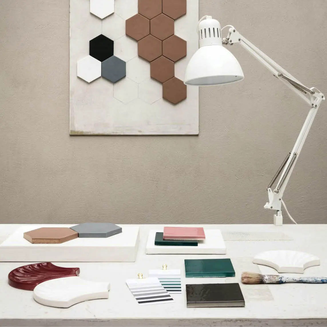Desk with ceramic tile samples, colour swatches and a white lamp