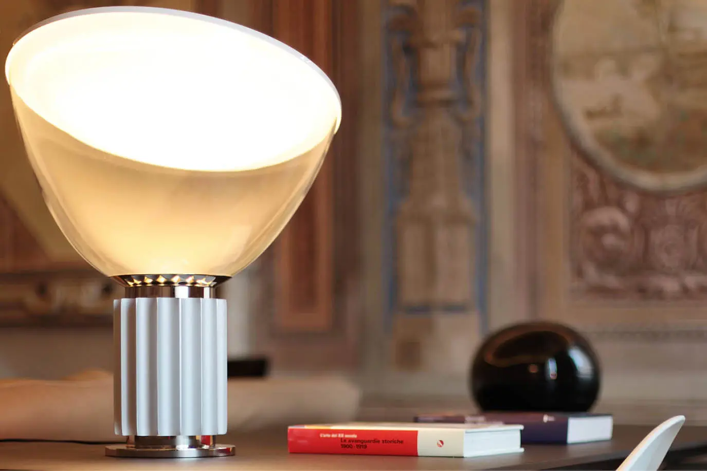 Table lamp and books in a room with frescoed walls