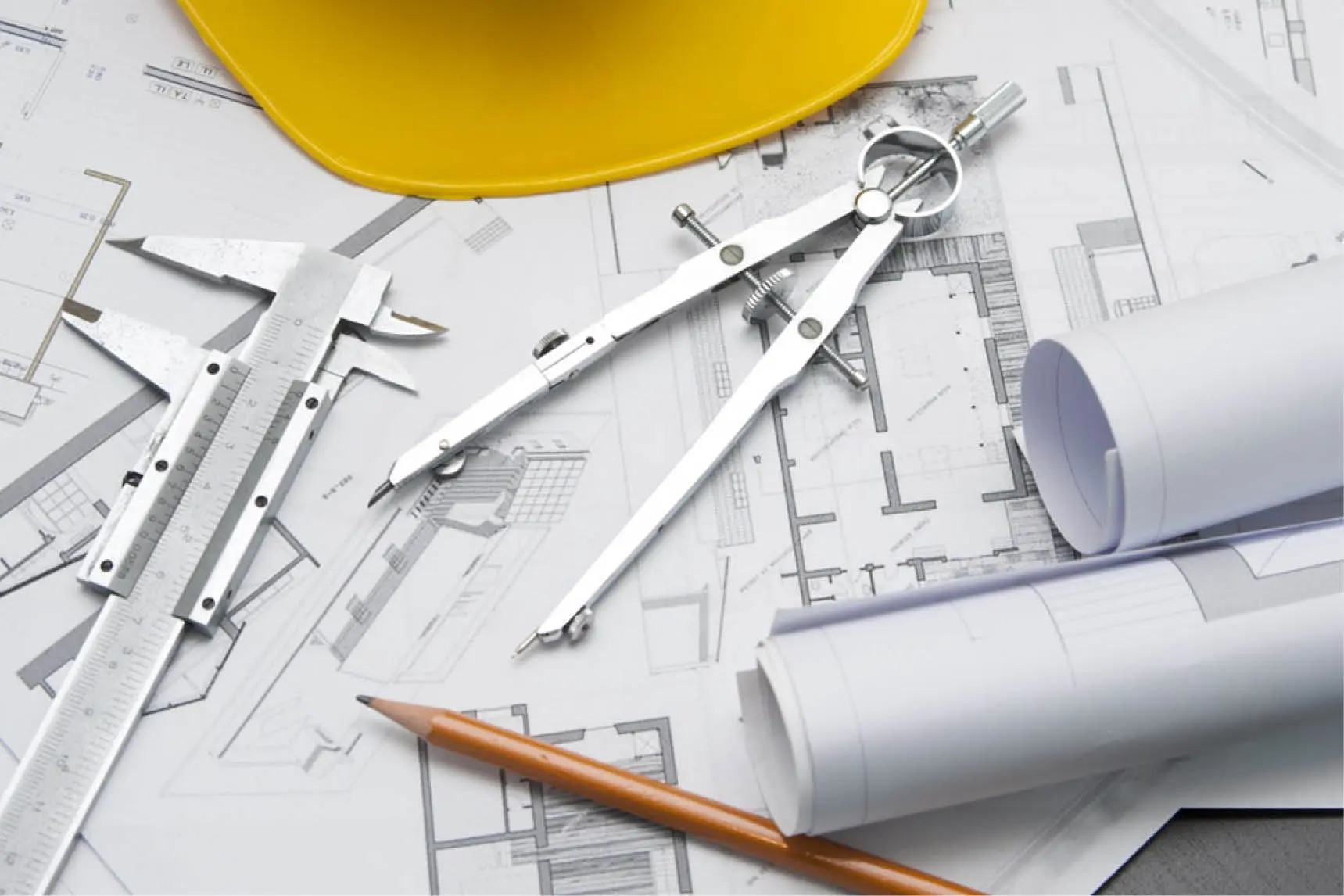 Architectural drawings with compass, calliper, pencil and hard hat