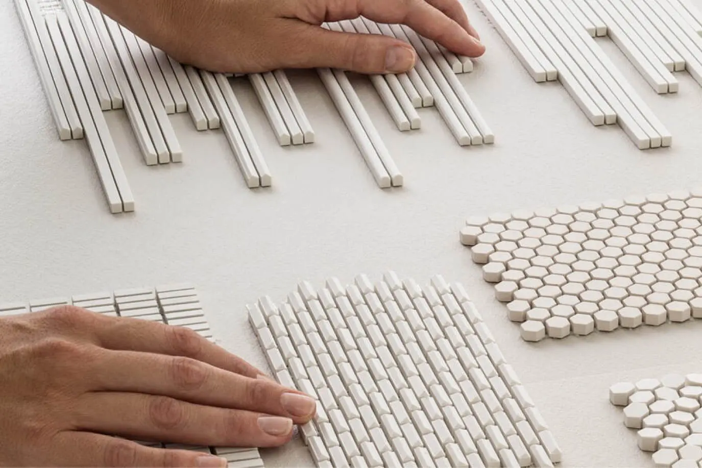 Hands arranging white mosaic tiles