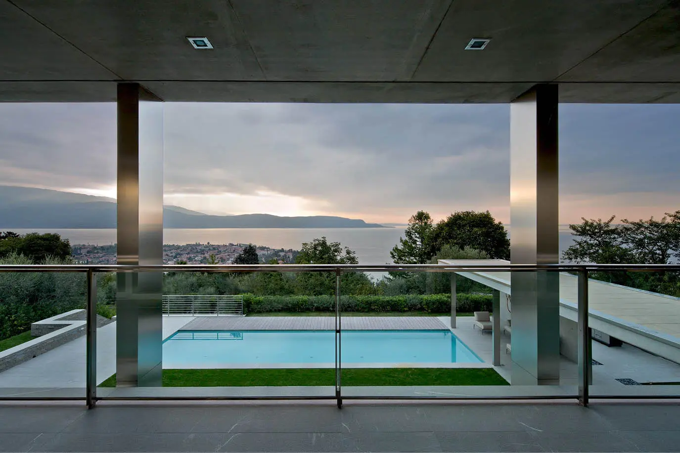 Covered terrace overlooking a pool and a lake at sunset