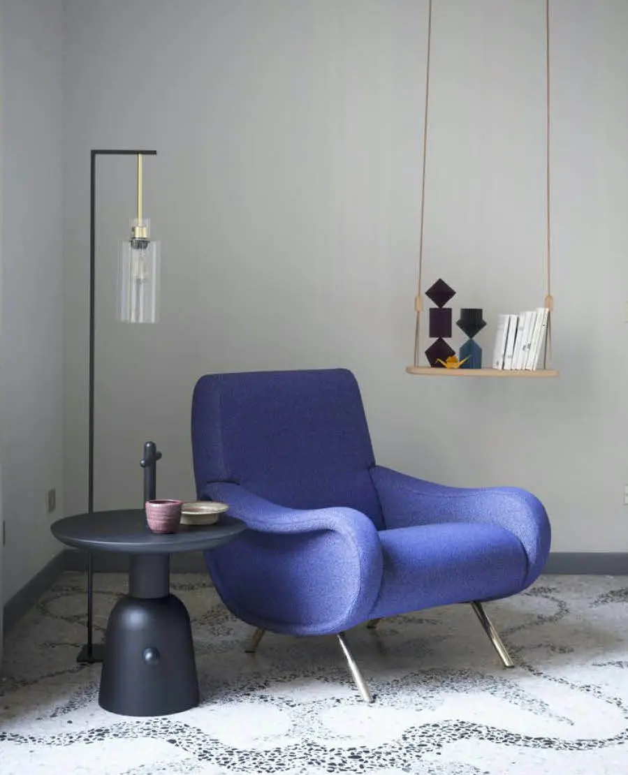 Blue armchair with a round side table and a hanging shelf