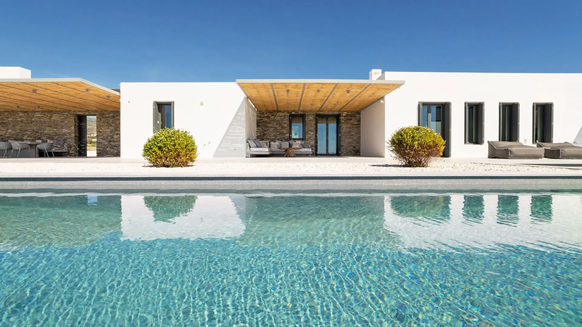 White modern house with a covered patio beside a swimming pool