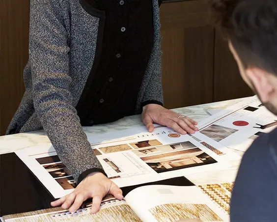 Two people reviewing design catalogs and mood boards on a table