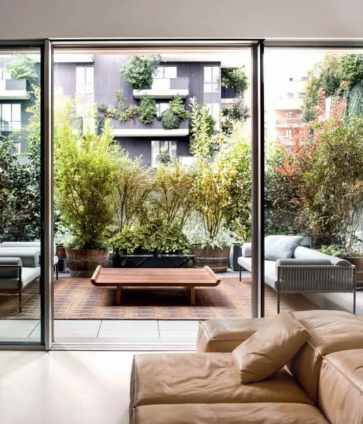 Living room with a leather sofa opening onto a planted terrace facing a green-covered building