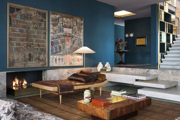 Eclectic living room with teal walls, framed artwork, a daybed, and a fireplace