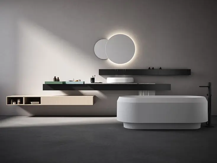 Bathroom display with round backlit mirrors, a floating vanity and an oval freestanding tub