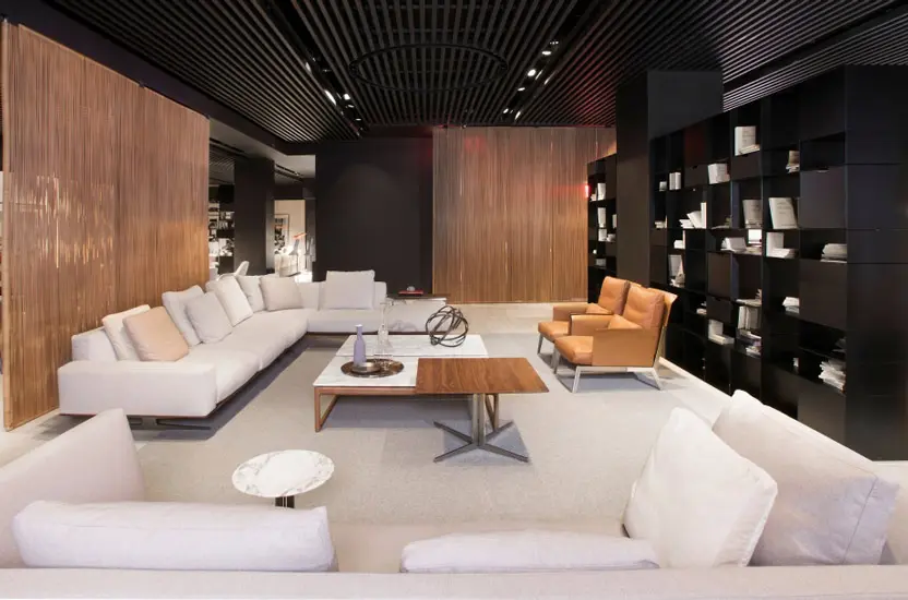 Furniture showroom with white sectional sofas, an orange leather armchair and dark wood display walls