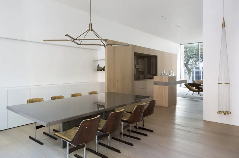 Dining room with a sculptural brass pendant light over a gray table and mismatched chairs