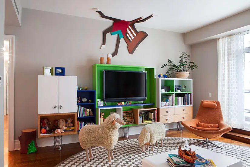 Playful kids room with a green TV console, sheep figures and a wall sculpture of a falling figure