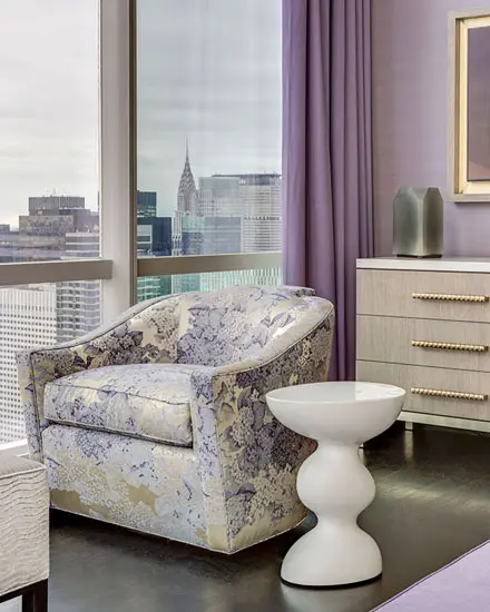 armchair by a window with the Chrysler Building visible on the skyline