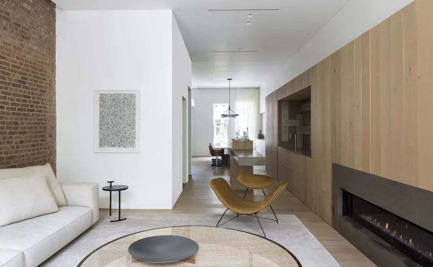 hallway with a brick accent wall opening to a dining area and wood cabinetry
