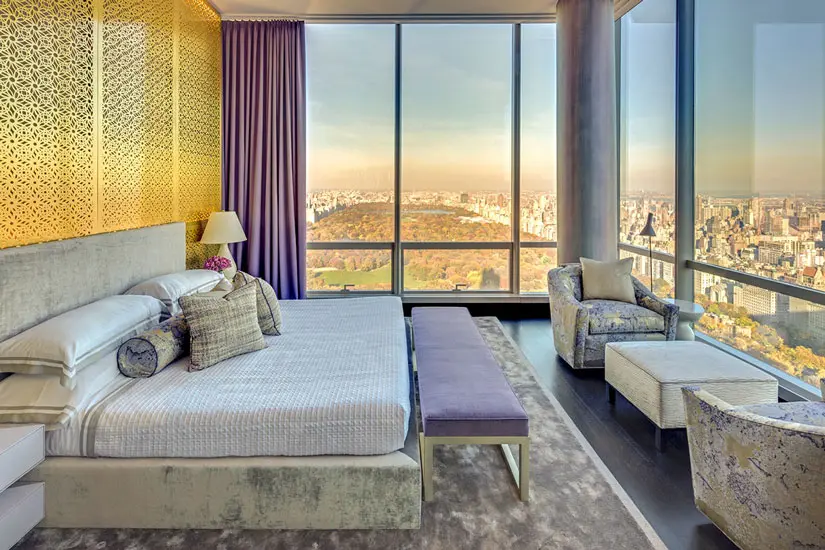 Bedroom with a gold patterned headboard wall and floor-to-ceiling windows over Central Park