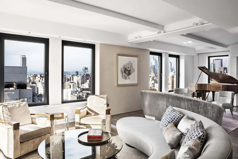 living room with city skyline views, a grand piano and a curved grey sofa
