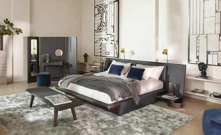 Bedroom with a dark grey upholstered bed, navy and grey pillows and a wooden bench at the foot of the bed