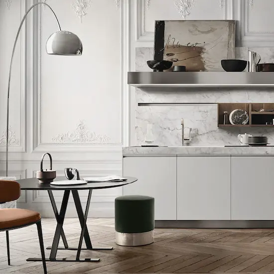 Marble kitchen backsplash and open shelving beside a round dining table in a stucco-walled room