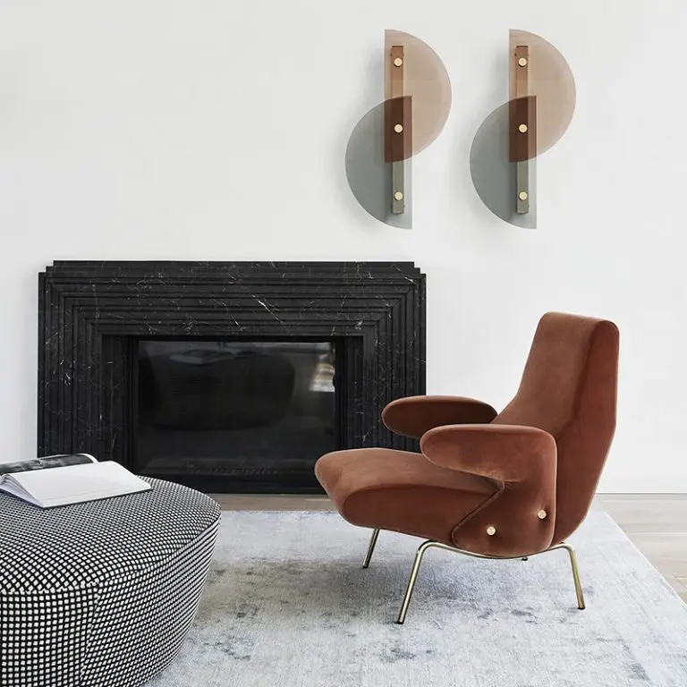Living room with a rust velvet Arflex armchair, black marble fireplace and geometric wall sconces