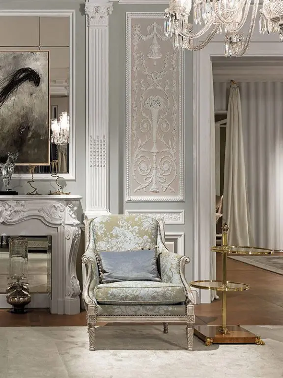 Classic living room with a floral upholstered wingback armchair, ornate white boiserie walls and a crystal chandelier