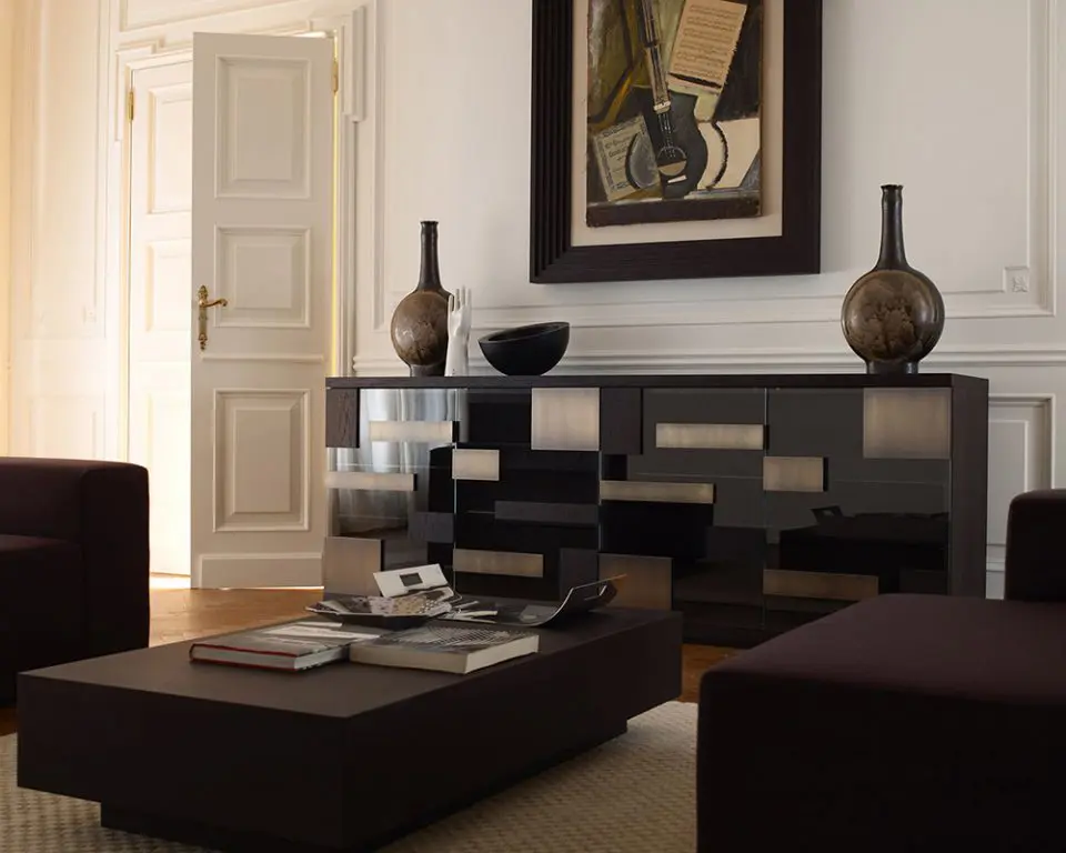 Dark wood and mirrored sideboard with bronze detailing beneath a framed painting in a classic living room