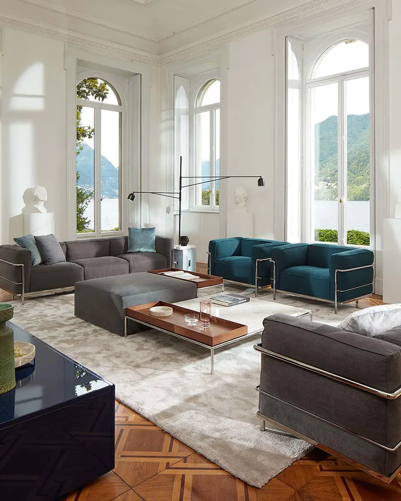 Living room with grey and teal Cassina Le Corbusier armchairs overlooking a lake